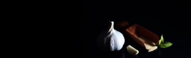 Diente de ajo fresco sobre fondo negro. El ajo es rico en vitaminas, primavera útil, buenas especias. Ajo en rodajas sobre un fondo oscuro. Ajo crudo en rodajas.