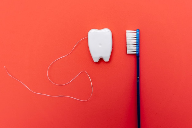 Diente de brillo blanco con cepillo de dientes sobre fondo rojo. Tratamiento con diente.