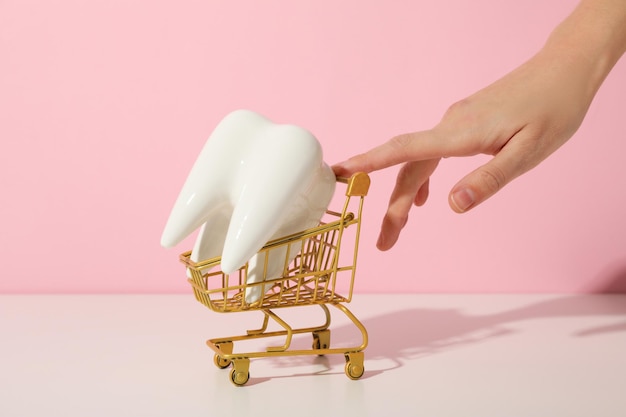 Foto un diente en un carrito de compras sobre un fondo rosa