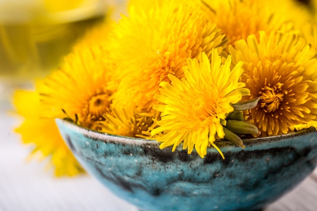 Diente de león. Cabezas de diente de león amarillo en tazón o mesa.