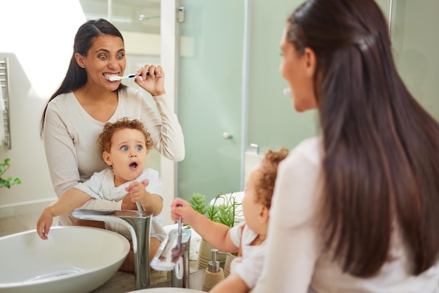 Foto dientes dentales y salud con una madre y un bebé cepillándose los dientes en el baño de su casa juntos higiene bucal infantil y atención médica con una mujer y su hijo usando un cepillo de dientes por la mañana
