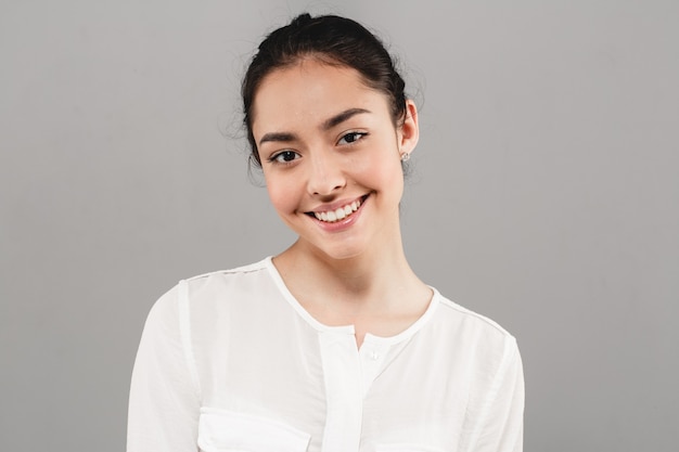 Dientes sanos sonríen mujer piel limpia maquillaje natural retrato femenino sobre fondo gris. Tiro del estudio.