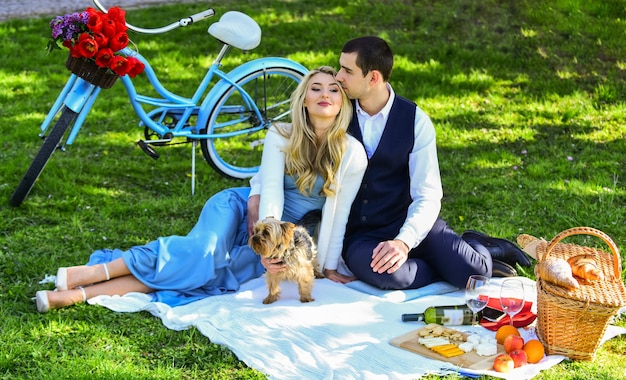 Dies ist Liebe, glückliches Paar in Liebe, Frau und Mann, die im Park liegen und den Tag zusammen genießen. Valentinstag-Picknick, romantisches Picknick im Park mit Hund