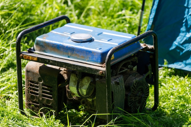 Dieselgenerator steht auf dem Gras neben dem Zelt. Foto in hoher Qualität