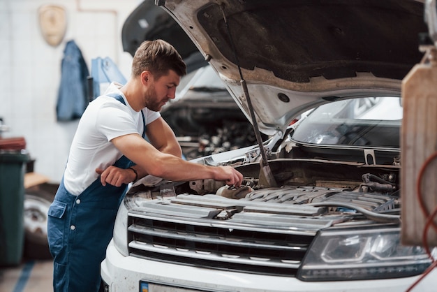 Foto dieser mann weiß, was sein job ist. mitarbeiter in der blau gefärbten uniform arbeitet im autosalon