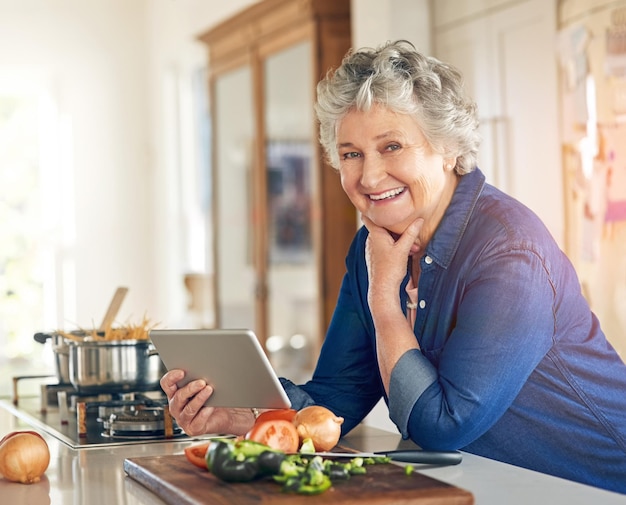 Dieses Rezept enthält sogar ein Video-Tutorial Porträt einer Seniorin, die beim Kochen in ihrer Küche ein digitales Tablet verwendet