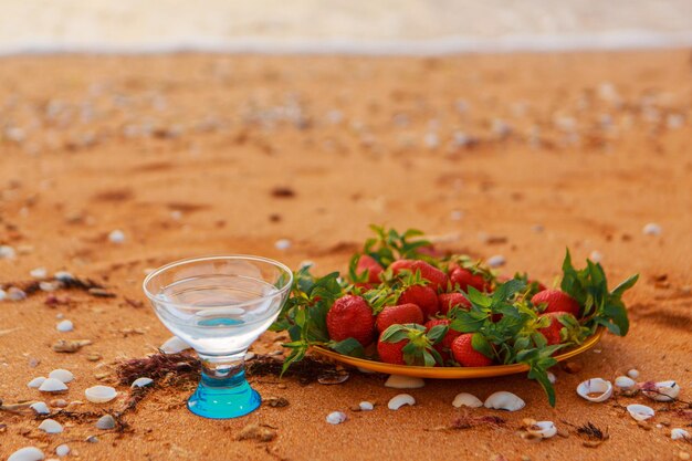 Dieta. Alimentação saudável e descanso. água limpa no fundo de vidro do mar e come morangos na praia