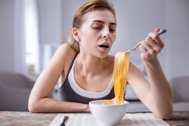 En una dieta. Bonita mujer joven sentada a la mesa mientras está a dieta