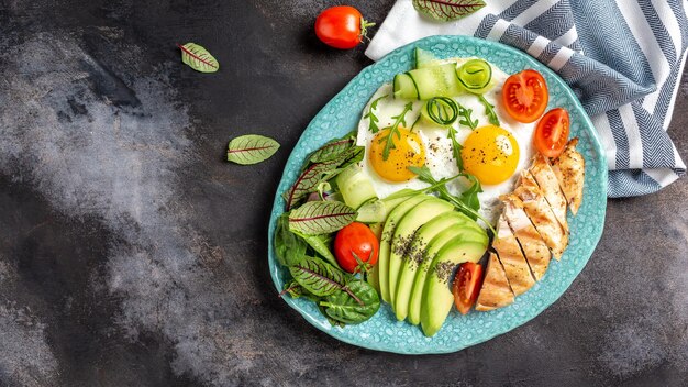 Dieta cetogênica café da manhã ovos fritos com tomate cereja abacate frango filé grelhado pepinos e abacate Café da manhã saudável vista superior