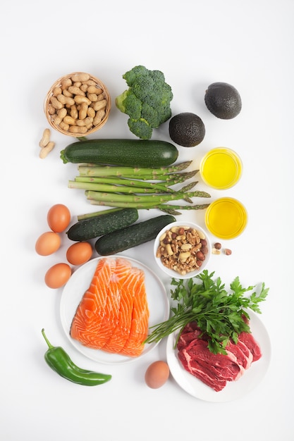 Dieta cetogênica, ceto, incluindo legumes, carne e peixe, nozes e óleo no fundo branco