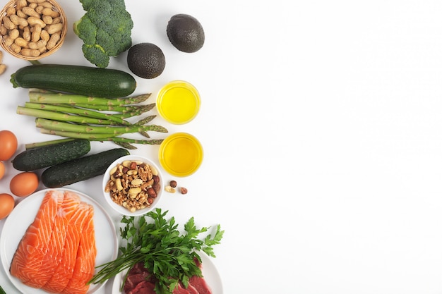 Dieta cetogénica, cetogénica, que incluye verduras, carne y pescado, nueces y aceite sobre fondo blanco con espacio de copia