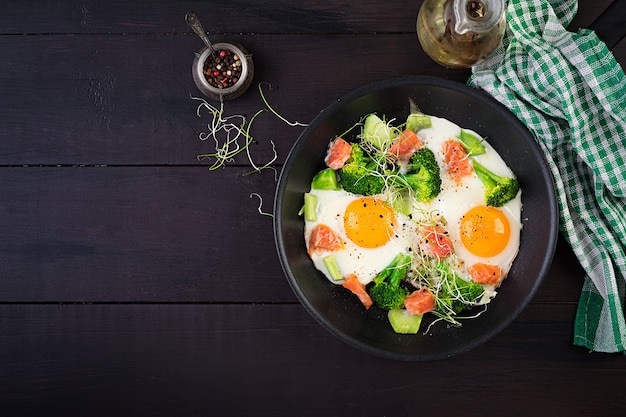 Dieta cetogênica / paleo. Ovos fritos, salmão, brócolis e microgreen. Café da manhã Keto. Escovar. Vista superior, sobrecarga
