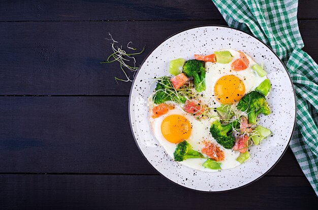 Dieta cetogênica / paleo. Ovos fritos, salmão, brócolis e microgreen. Café da manhã Keto. Escovar. Vista superior, sobrecarga