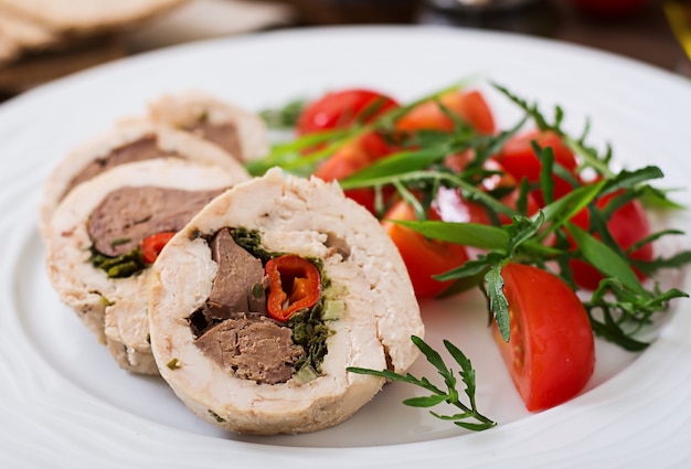 Dieta cocida al horno rollos de hígado de peluche, chile y hierbas con una ensalada de tomates y rúcula. Menú dietético. Nutrición apropiada.