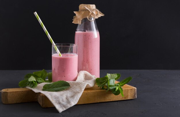 Dieta, comida sana. Yogur de bayas o batido en vidrio sobre tabla de madera, naturaleza muerta, fondo oscuro.