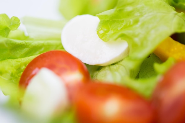 dieta, comida vegetal, alimentación saludable y concepto de objetos: cierre de ensalada de verduras con queso mozzarella