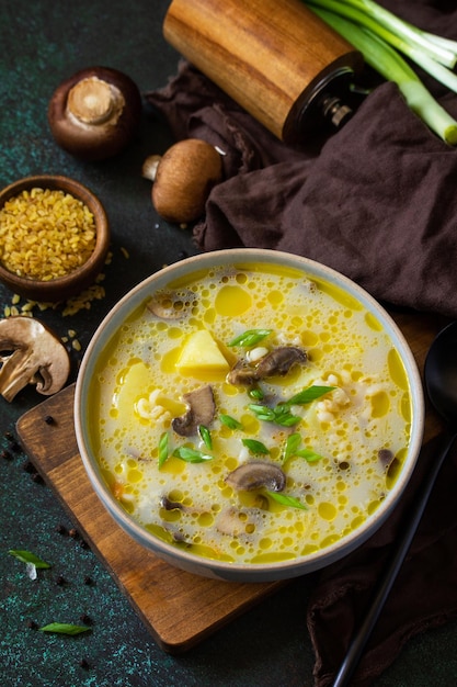 Dieta y concepto de alimentación saludable Sopa de crema de champiñones reales con bulgur sobre un fondo de piedra oscura