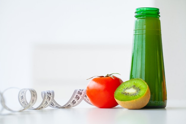 Dieta. Concepto de dieta saludable y fitness, jugo verde. Fruta fresca y vaso de agua, cinta métrica