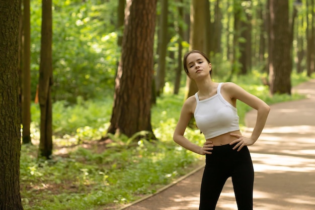 Dieta deportiva estilo de vida saludable Niña calentándose en el parque antes de trotar haciendo ejercicios en la naturaleza