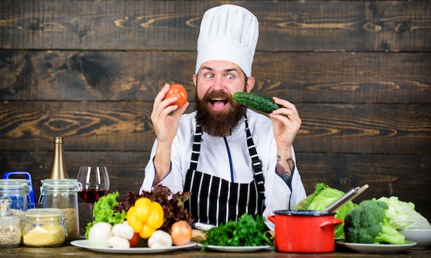 Dieta de desintoxicación Chef profesional en uniforme de cocinero Hombre barbudo feliz cocinando en la cocina Dieta con alimentos orgánicos Verduras frescas Alimentos saludables y vegetarianos Vitamin man use utensilios de cocina