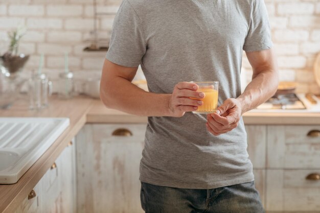 Dieta de desintoxicación de frutas Captura recortada del hombre de pie en la cocina con un vaso de jugo de naranja orgánico fresco