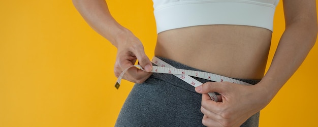 Dieta y dieta Belleza cuerpo femenino delgado use cinta métrica Mujer en ropa de ejercicio logra el objetivo de pérdida de peso para una vida saludable loca por la delgadez nutricionista de cintura delgada
