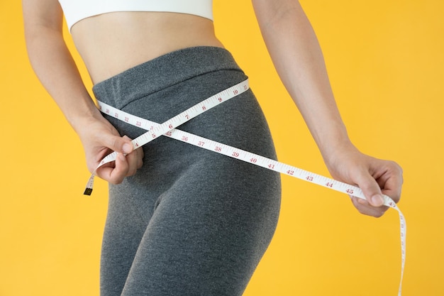 Dieta y dieta Belleza cuerpo femenino delgado use cinta métrica Mujer en ropa de ejercicio logra el objetivo de pérdida de peso para una vida saludable loca por la delgadez nutricionista de cintura delgada