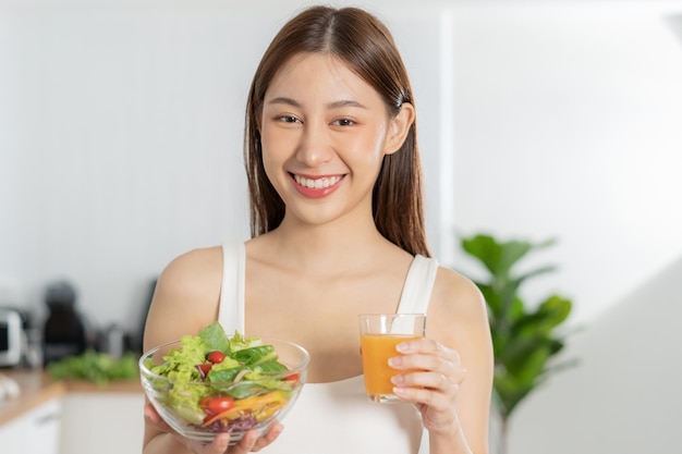Dieta dieta jovem asiática ou menina sorrindo segurando um copo de suco de laranja e misturar legumes tigela de salada verde comer comida com baixo teor de gordura bom saudável nutricionista perda de peso saúde pessoa