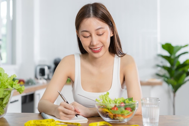 Dieta Dieta mujer joven asiática trabajando escribir plan de dieta nutrición correcta elegir mezclar verduras ensalada alimentos para una buena salud Nutricionista mujer Pérdida de peso persona