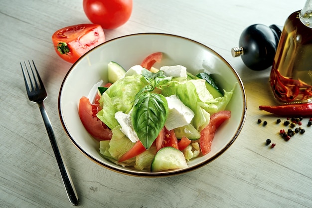 Dieta e deliciosa salada de vegetais com queijo feta, servida em uma tigela azul sobre uma mesa de madeira. Comida saudável.