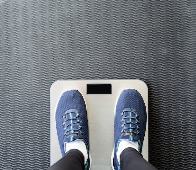 Dieta e perda de peso. Vista superior de pés femininos em calçados esportivos em escalas