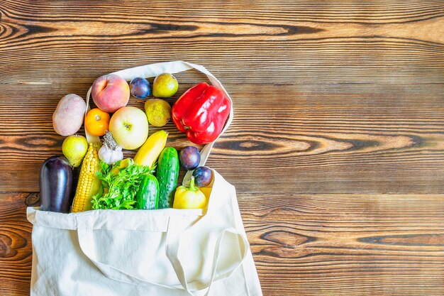 Foto dieta fitness vegetariana comida vegana para la cena con frutas y verduras frescas en algodón textil eco bolsa de adelgazamiento ecología concepto de compra en fondo de madera copia espacio vista superior plana plana