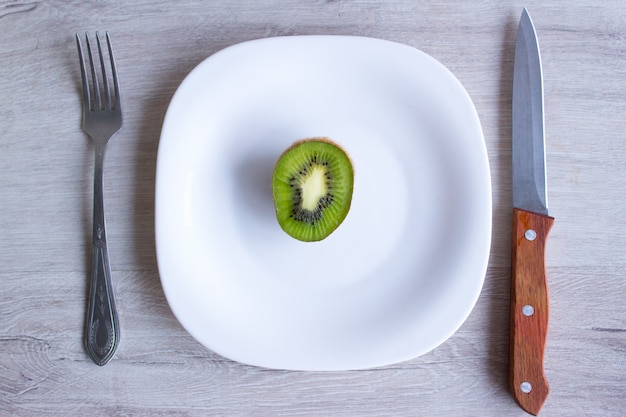 Dieta de frutas, kiwi. Un tenedor y un cuchillo en madera. Rápido.