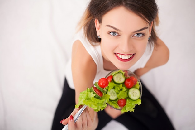 Dieta. Hermosa mujer joven comiendo ensalada de verduras