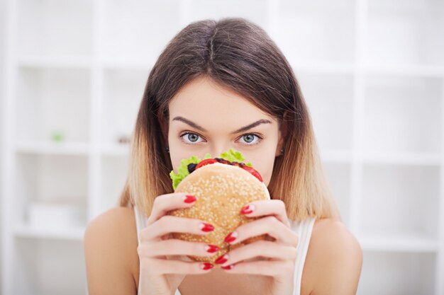 Dieta. Mujer joven con cinta adhesiva sobre su boca, evitando que coma comida chatarra. Alimentación saludable