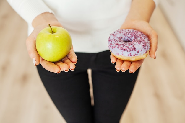 Dieta, mujer midiendo el peso corporal en la balanza sosteniendo Donut y manzana,