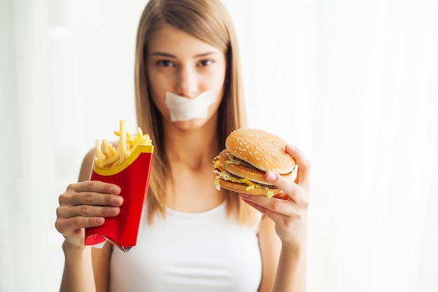 Dieta, mulher retrato quer comer um hambúrguer, mas boca skochem preso, o conceito de dieta, junk food, força de vontade em nutrição