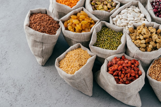 Dieta, nutrição e conceito de alimentação saudável. Cereais coloridos e frutos secos ricos em proteínas em sacos de estopa. Sementes de legumes secos.