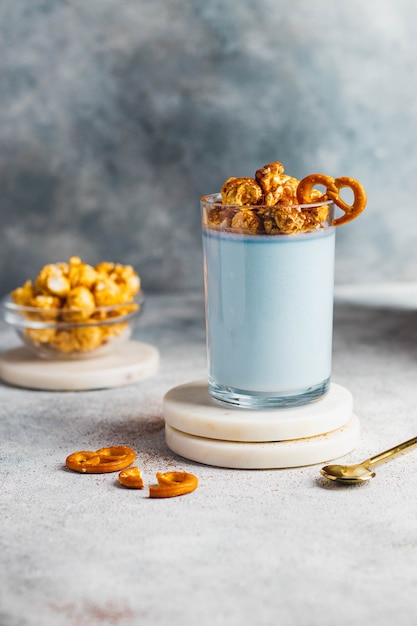 Foto dieta panna cotta con yogur griego, leche de coco, espirulina azul decorada con palomitas de maíz y pretzel en el vaso. concepto probiótico desayuno saludable. de cerca