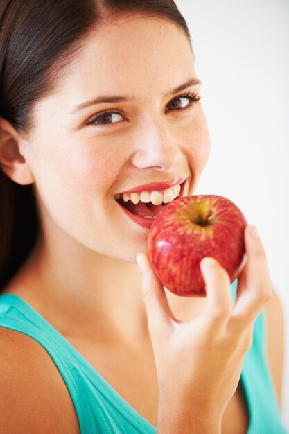 Foto dieta y retrato de mujer con manzana comiendo para nutrición bienestar y bocadillo en el estudio alimentación feliz y rostro de persona con fruta para vitaminas desintoxicación y pérdida de peso en fondo blanco