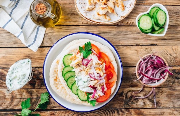 Dieta saludable pollo Gyros sándwich envuelto en pan de pita griego con rodajas de carne tzatziki y verduras frescas Fondo rústico de madera Vista superior