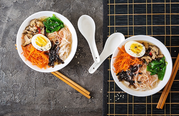 Dieta tigela vegetariana de sopa de macarrão de cogumelos shiitake, cenoura e ovos cozidos. comida japonesa vista do topo. configuração plana