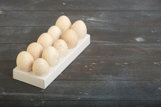 Diez huevos de pavo con caja de plástico blanco fondo de madera teñida áspera