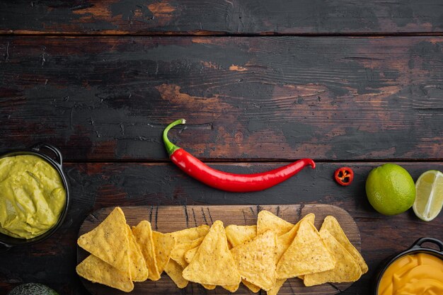 Diferentes aderezos y salsas para nachos en la vista superior de la mesa de madera antigua o en posición plana con espacio de copia para texto