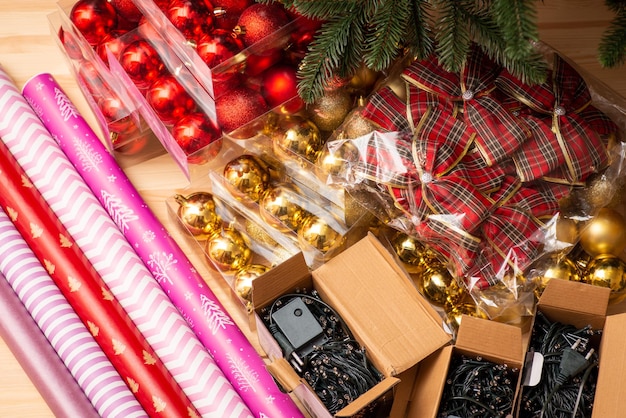 Diferentes adornos navideños en la mesa Burbujas rojas y amarillas Arcos Guirnaldas de papel de regalo de colores Algunas ramas de árboles de Navidad artificiales Decoraciones navideñas