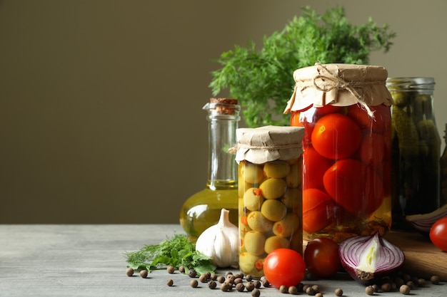 Diferentes alimentos e ingredientes en escabeche en mesa de madera gris