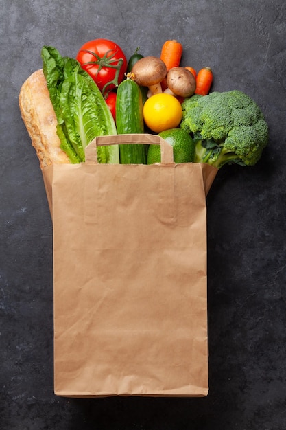 Diferentes alimentos saudáveis na reciclagem de saco de papel na mesa de pedra Vista superior plana com espaço de cópia