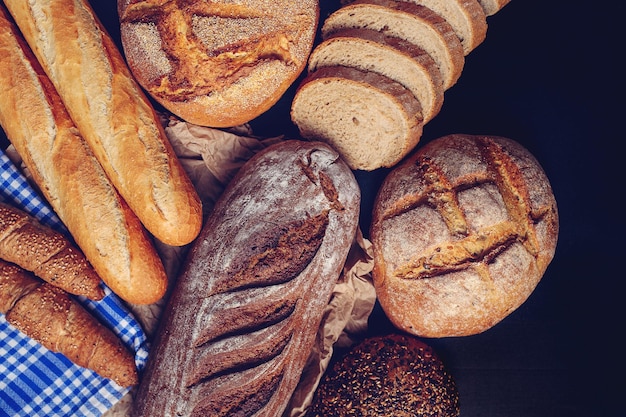 Diferentes amores de pan y baguettes colocados sobre un paño de cocina azul.