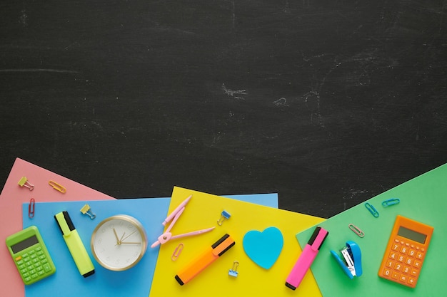 Diferentes artículos de papelería aislados en el fondo de la pizarra Concepto de educación o regreso a la escuela