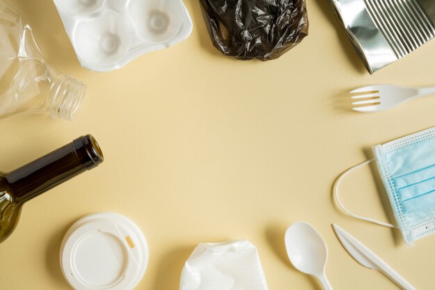 Diferentes basura reciclada de metal, plástico y otros sobre el fondo amarillo. Marco, lugar para texto, plano.